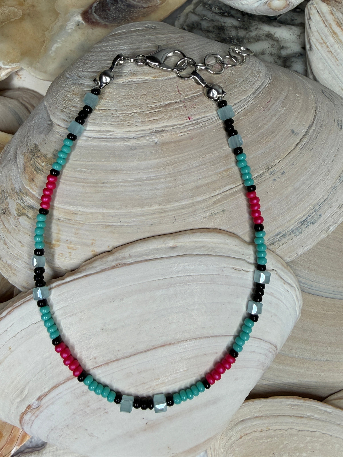 Wild Grace beaded bracelet in teal, coral pink, black, and light teal glass beads on seashells